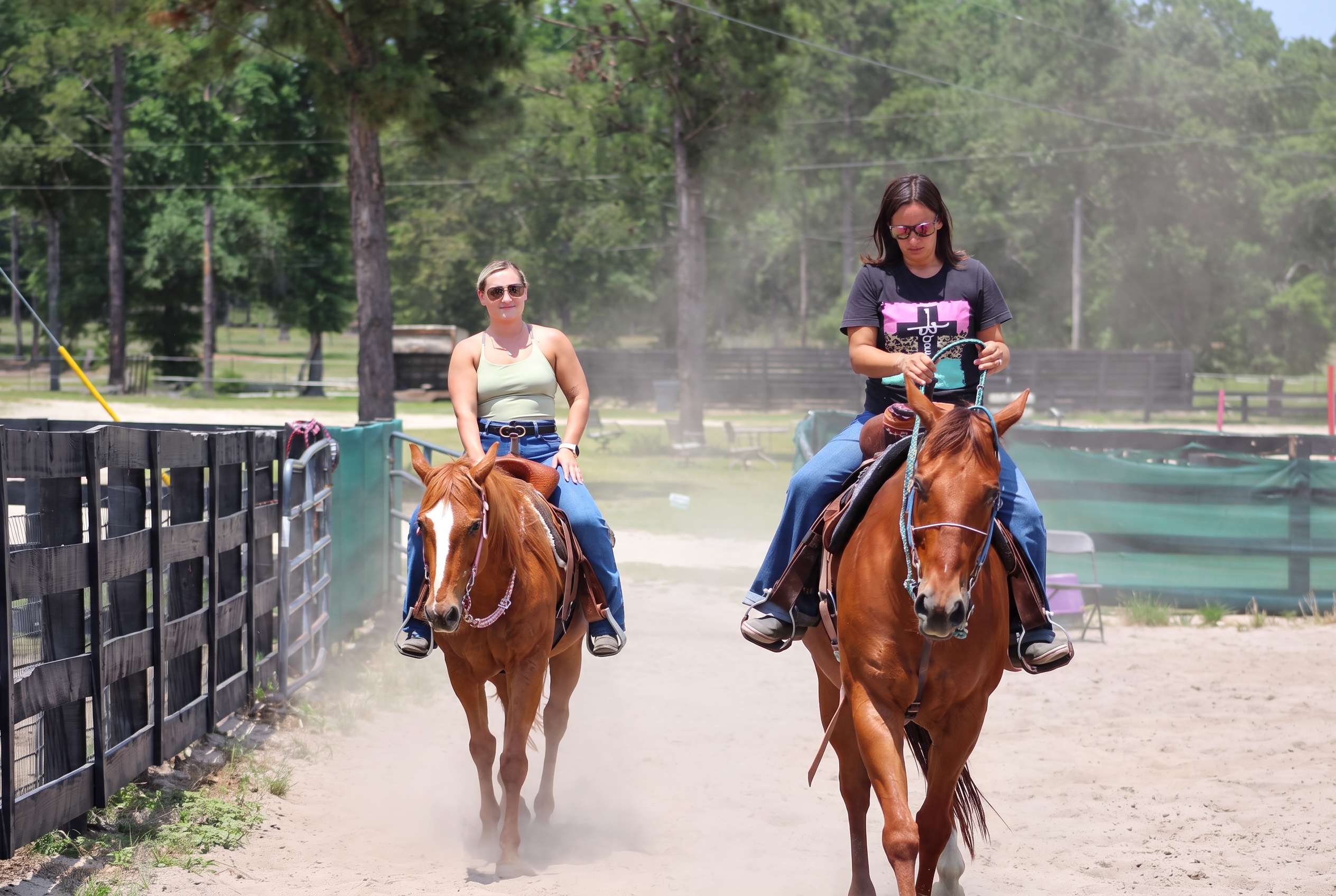 Two adults riding through golden arena dust