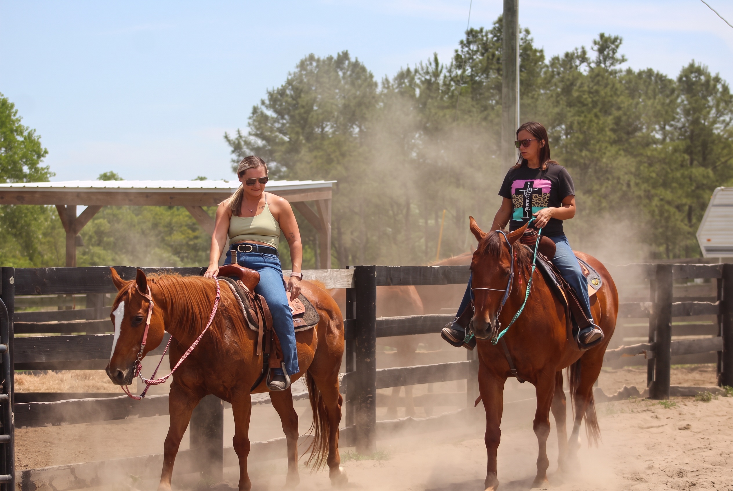 Two boarders riding their horses along the black fence line